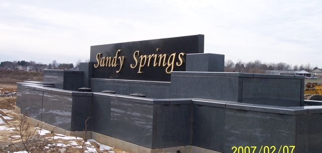 Sandy Springs sign on a dark stone monument in a snowy roadside setting