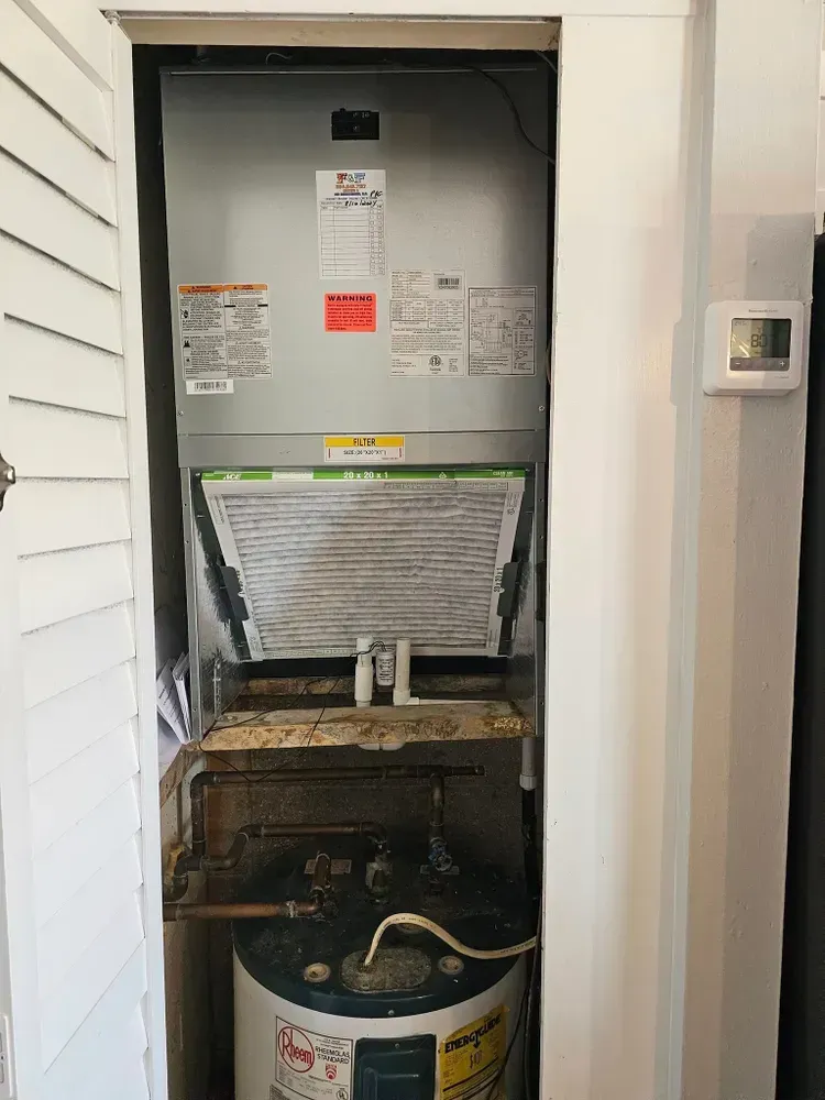 HVAC system and water heater in a closet. Air filter visible, thermostat on the wall.