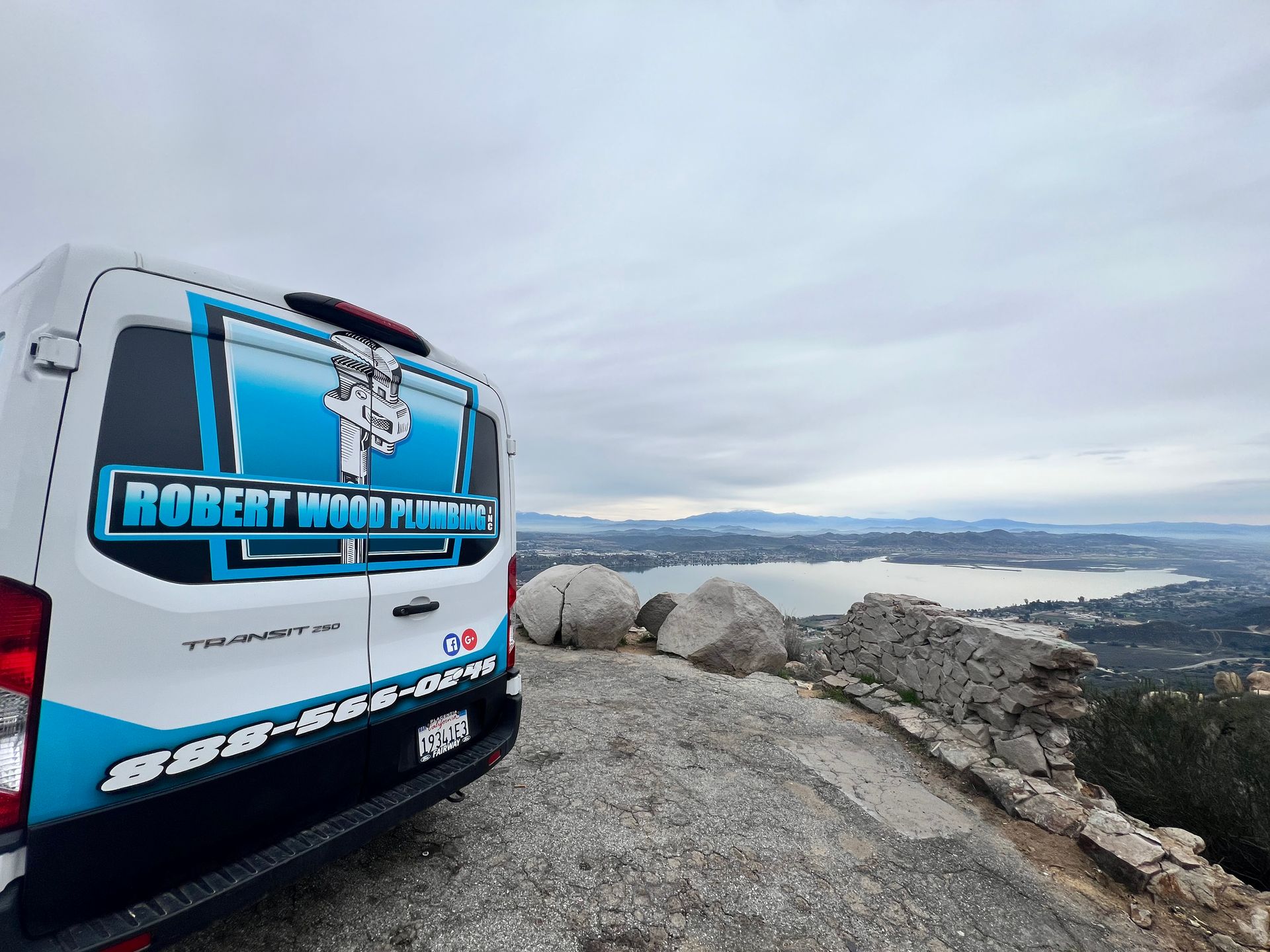 A white van is parked on top of a rocky hill.