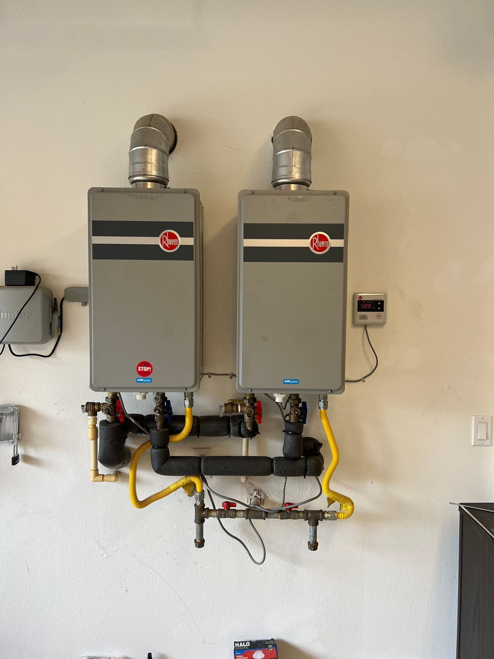 Two water heaters are mounted on a white wall