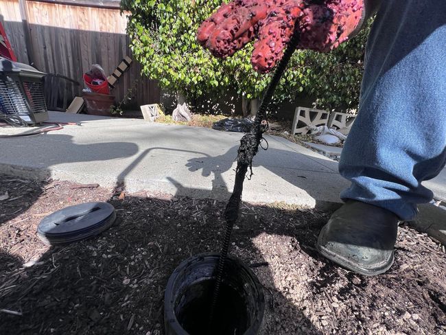 A person is digging a hole in the ground with a hose.