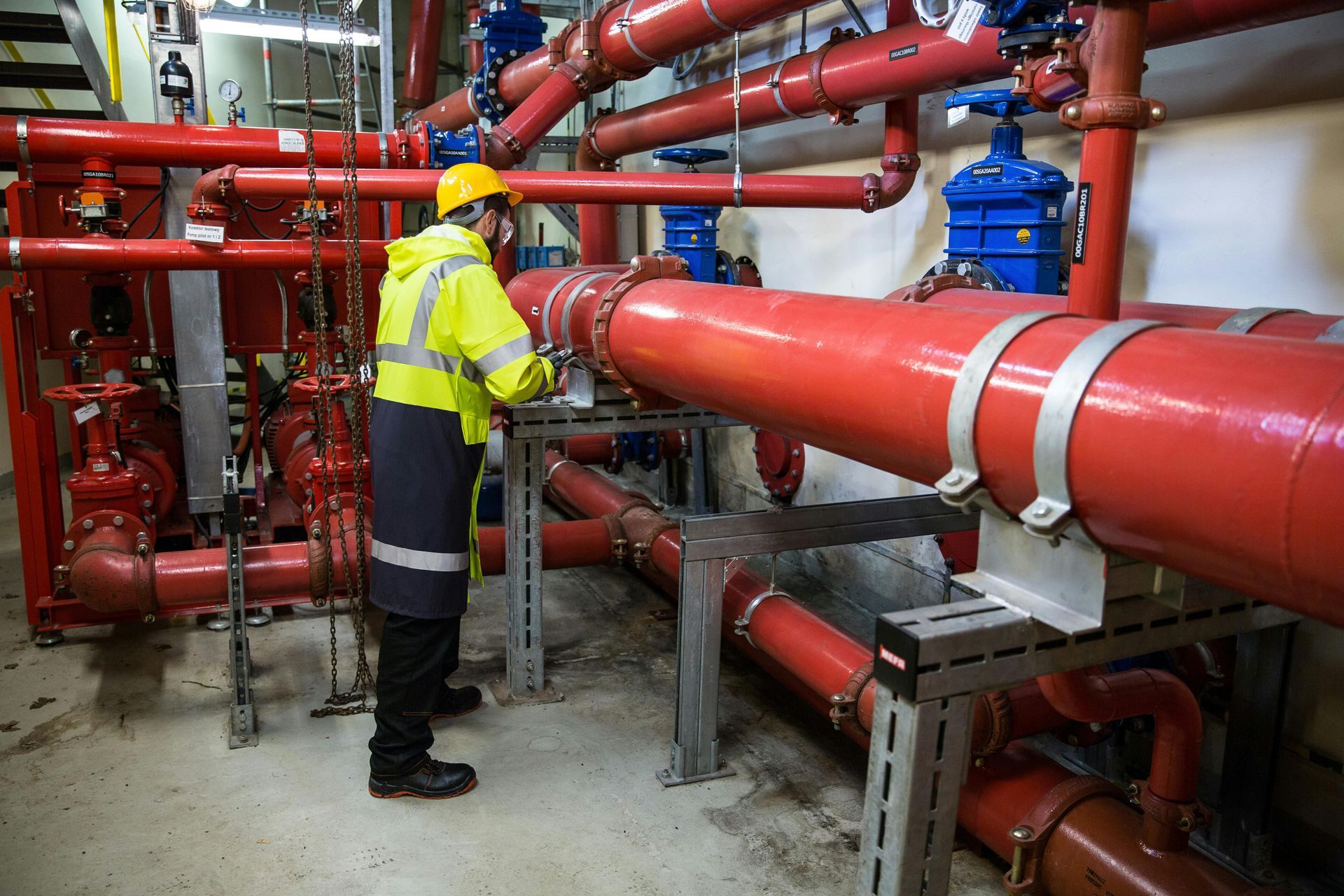 A man is standing in a room filled with red pipes.