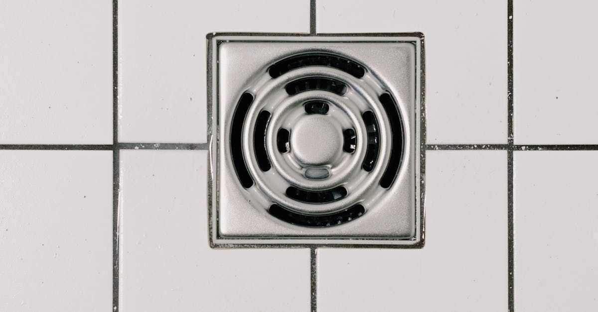 A close up of a drain on a tiled floor.