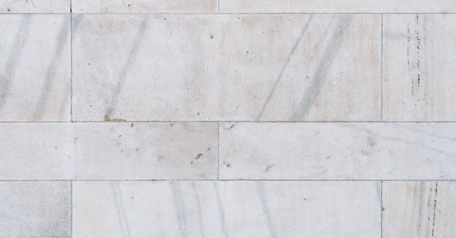 A close up of a white marble tile wall.