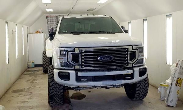 White Ford truck in a paint booth.