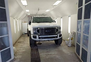Man holding a red gas can beside a white car on a road.