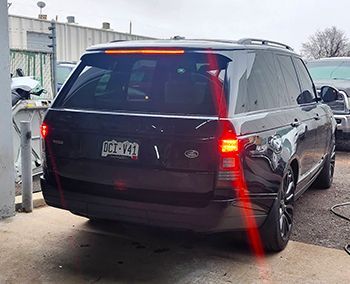 Black Range Rover SUV with brake lights on. Colorado license plate.