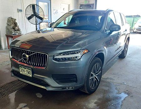 Gray Volvo SUV parked inside a garage, with front license plate visible.