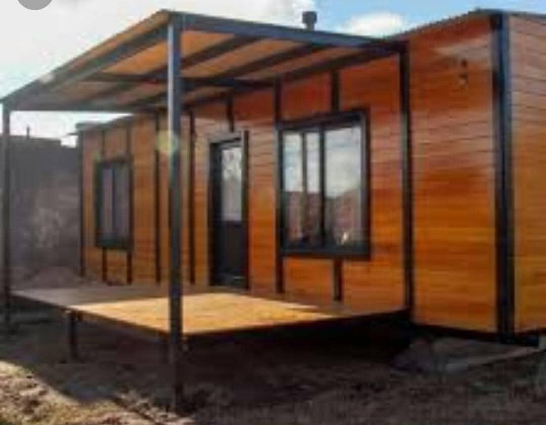 Casa modular de madera con porche cubierto y postes de metal negro en construcción.