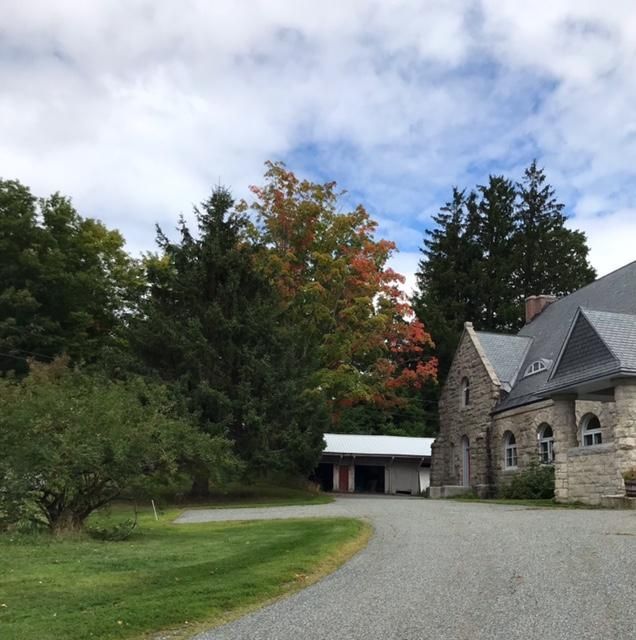 A gravel driveway leading to a stone house