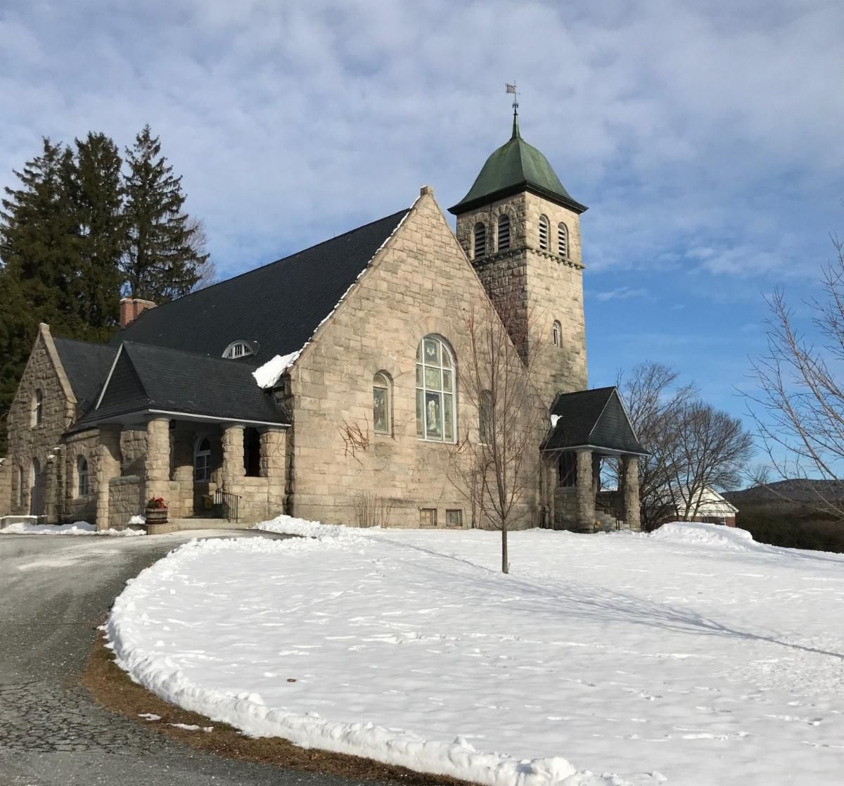 A church with a steeple is surrounded by snow