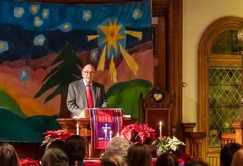 A man stands at a podium in front of a crowd of people
