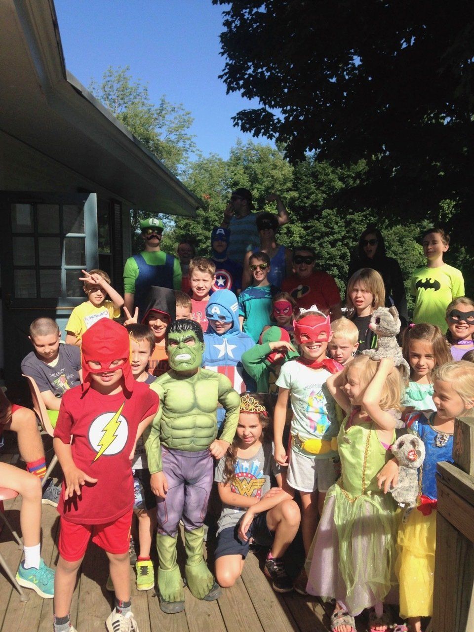 A group of children dressed in superhero costumes pose for a picture