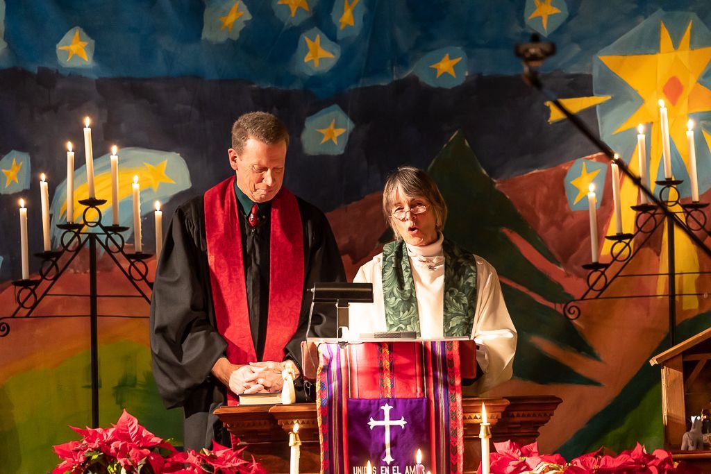 A man and a woman are standing in front of a podium with a cross on it