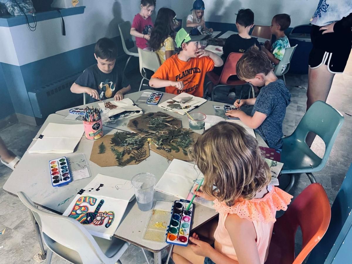 A group of children are sitting around a table painting with watercolors.