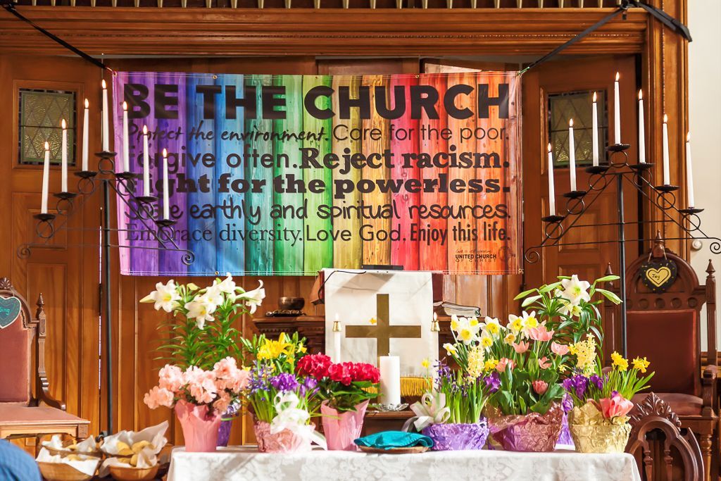 A church with flowers and a sign that says be the church