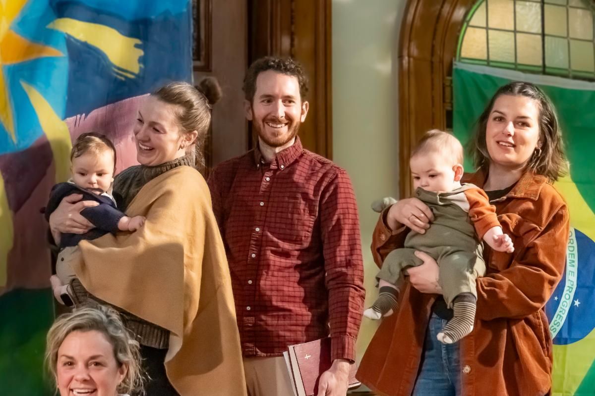 A group of people are posing for a picture in front of a brazilian flag.