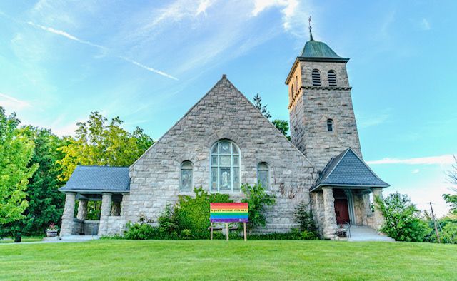 A church with a rainbow flag in front of it.