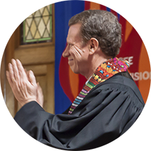 A man in a black robe is clapping his hands