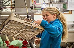 Two young girls are cleaning a dishwasher in a kitchen.