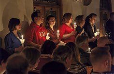 A group of people are holding candles in a dark room.