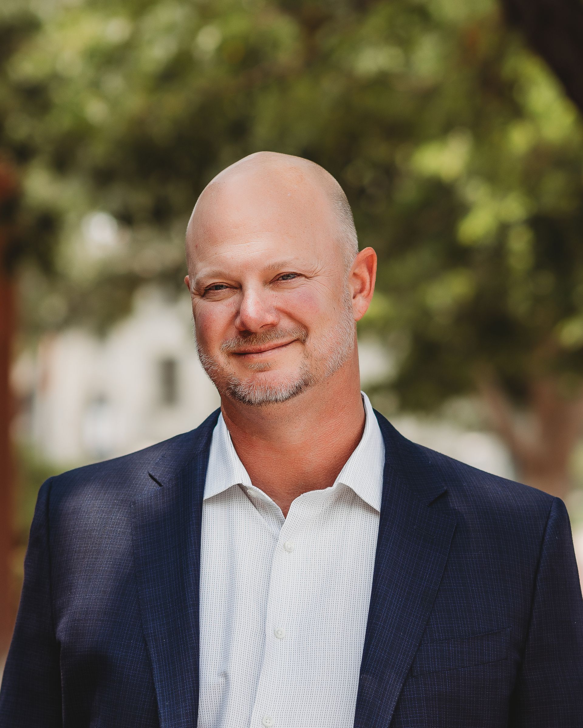 A man in a suit and white shirt is smiling for the camera.