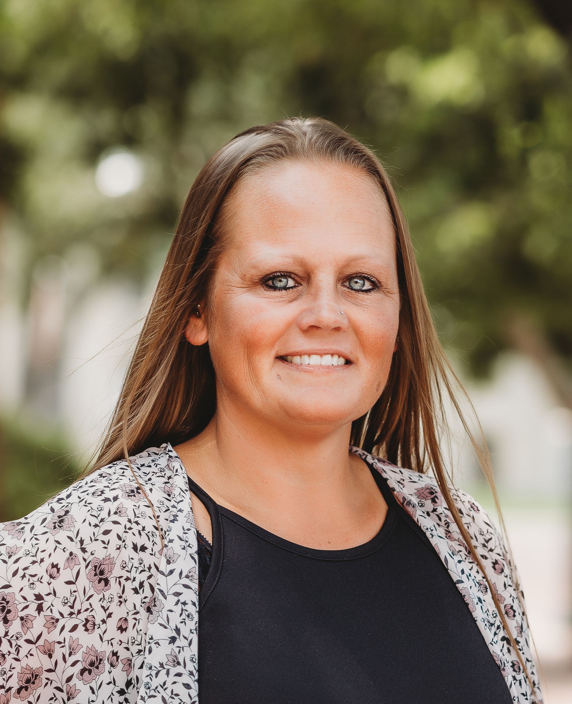 A woman with long hair and blue eyes is smiling for the camera.