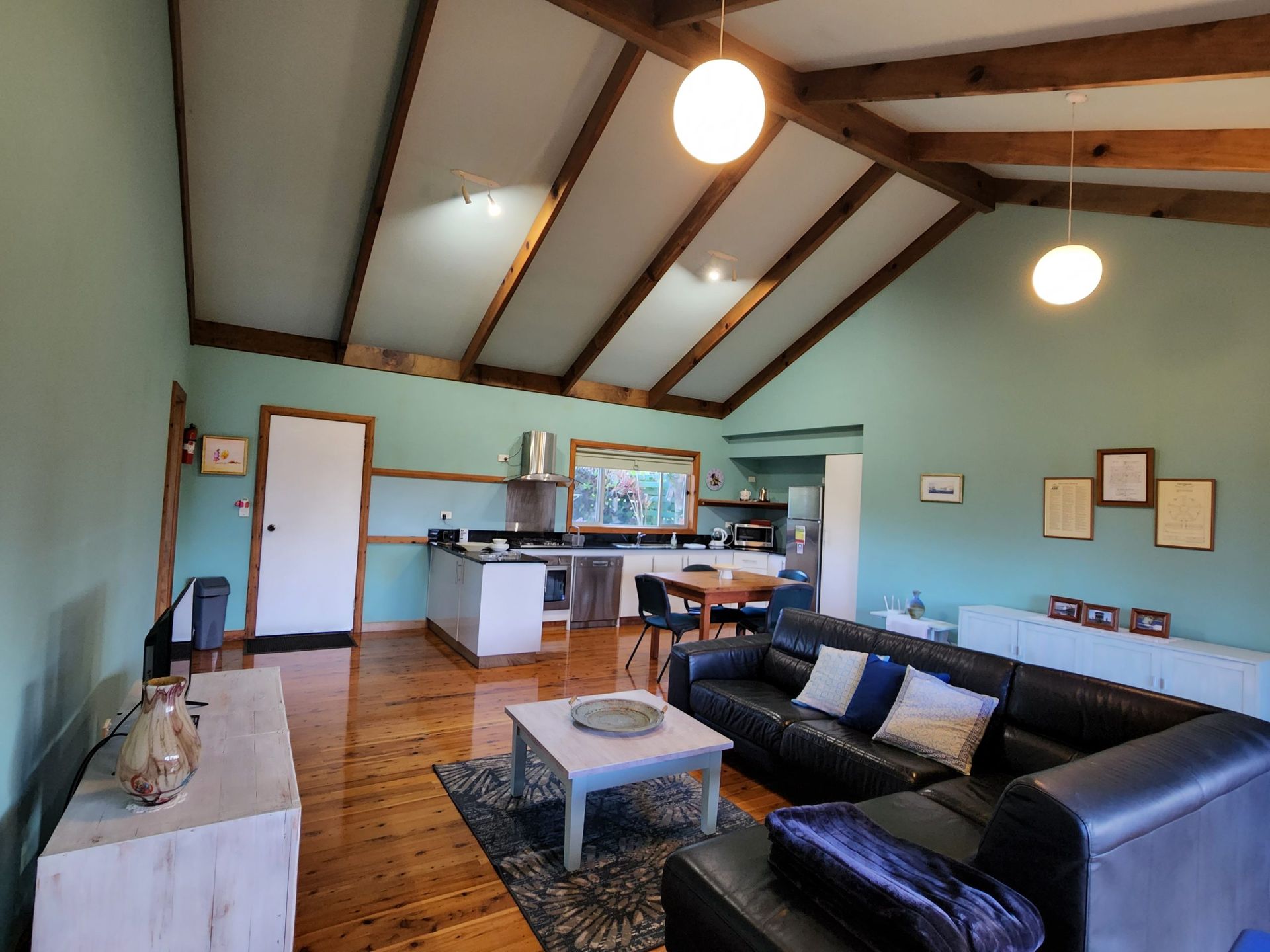Living room with teal walls, wood beams, black leather sofa. Norfolk Island Trade Winds Seniors Sanctuary