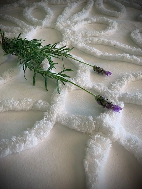 Lavender sprig on white, textured fabric with a sunburst design. Norfolk Island Trade Winds Seniors Sanctuary