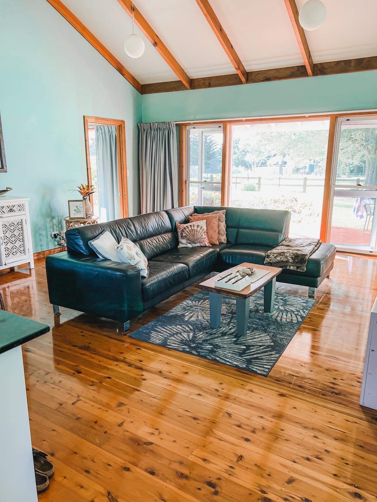 Living room with blue walls, leather sectional, wooden floors. Norfolk Island Trade Winds Seniors Sanctuary