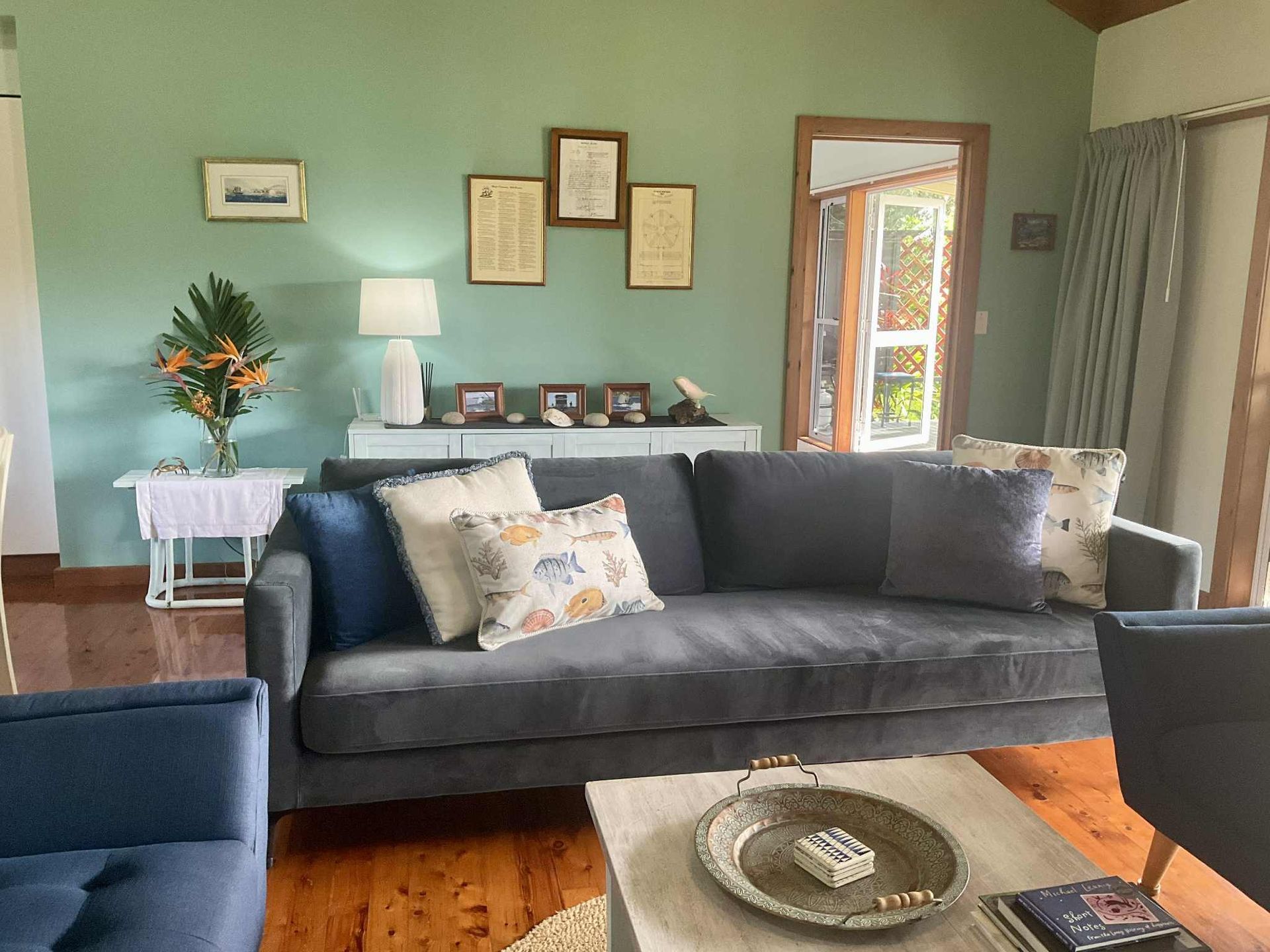 Living room with gray sofa, blue chairs, coffee table, and green walls. Norfolk Island Trade Winds Seniors Sanctuary