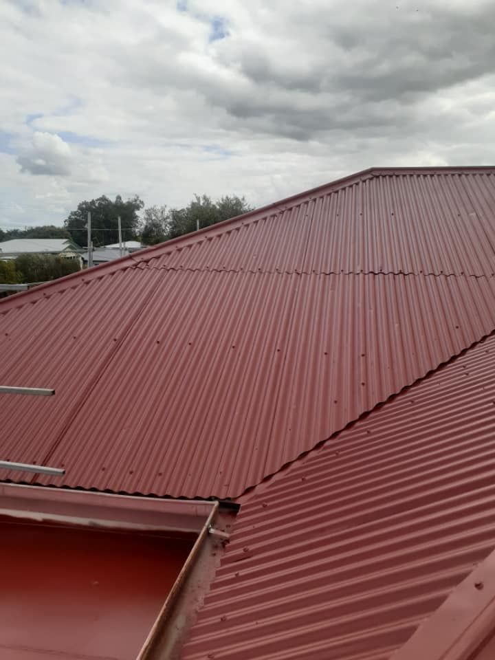 Red Corrugated Metal Roof Under a Cloudy Sky — Roof Tek CQ in Rockhampton, QLD