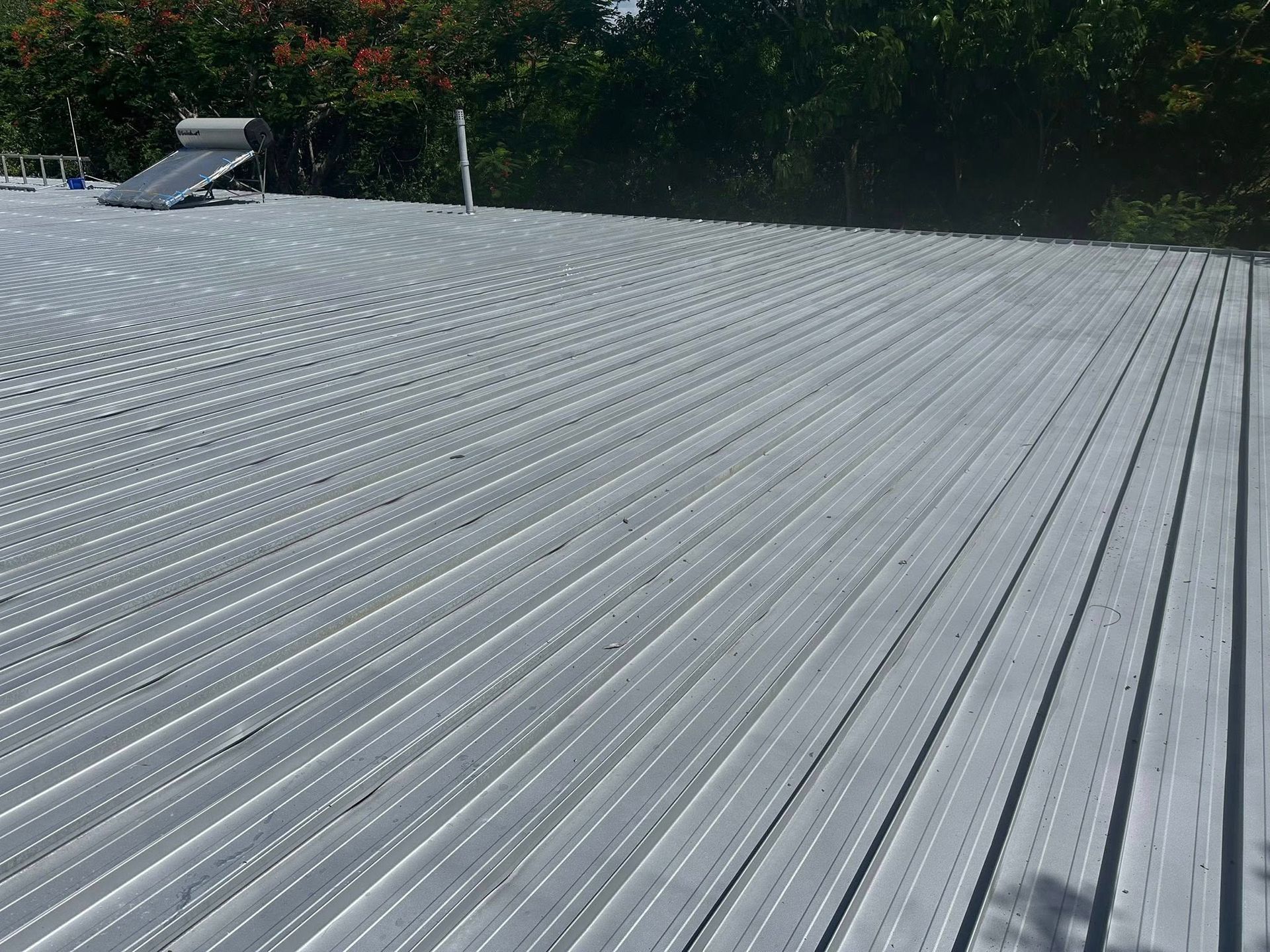 Person Using a Yellow Drill to Secure Metal Roofing to the Frame of a Roof — Roof Tek CQ in Rockhampton, QLD