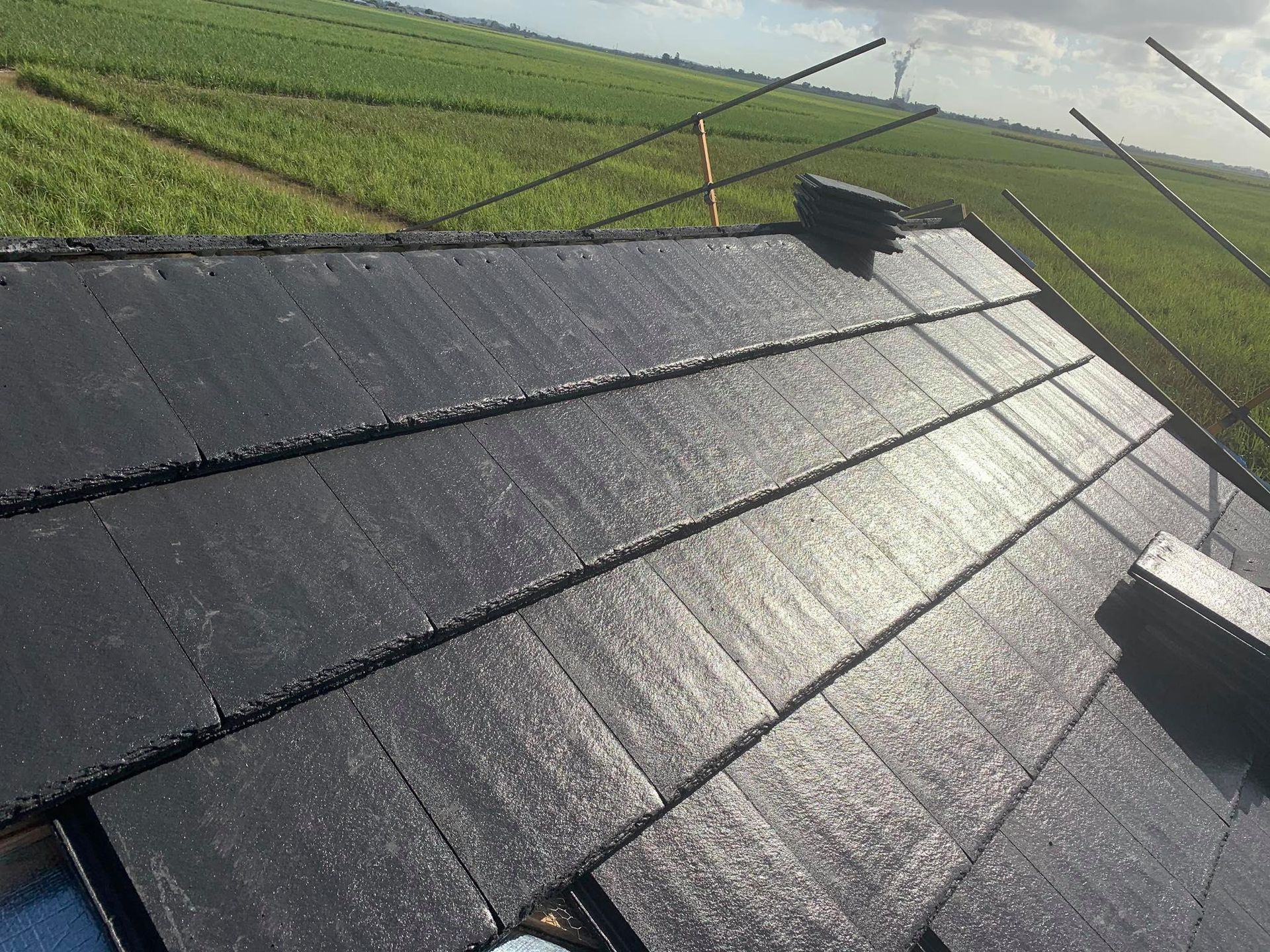 Dark Gray Roof Tiles on a Roof; Green Field Background — Roof Tek CQ in Rockhampton, QLD