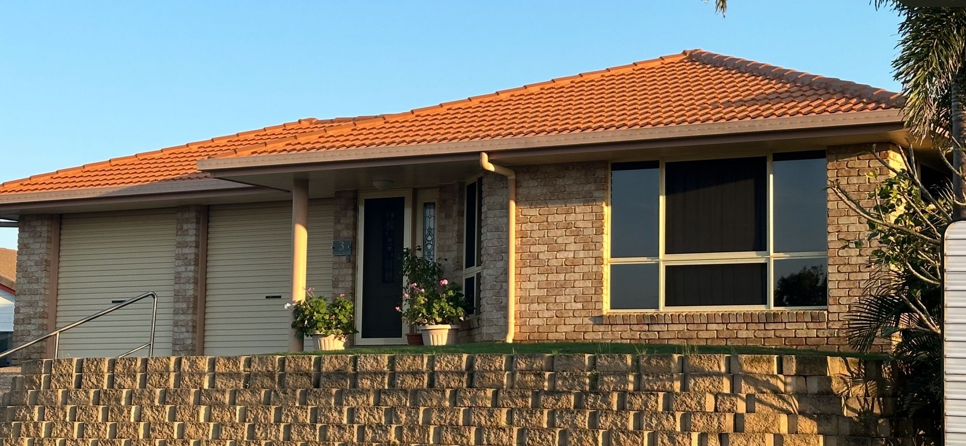 Brick house with terracotta roof, large windows, and a retaining wall — Roof Tek CQ in Gracemere, QLD