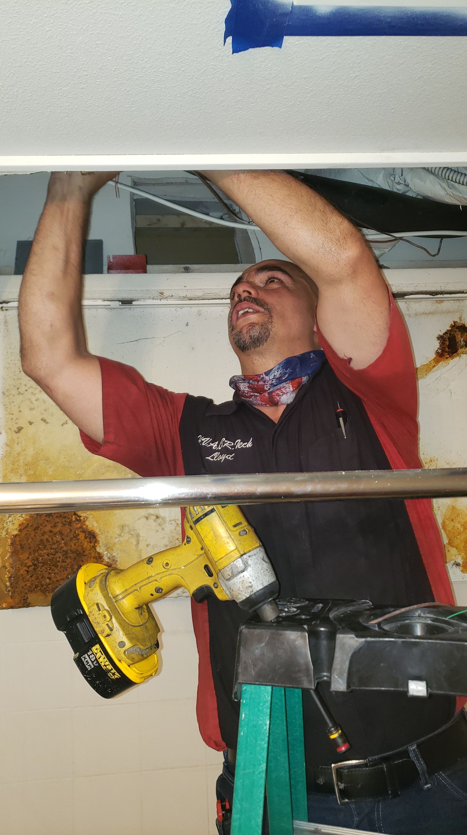 A man is working on a ceiling with a drill.