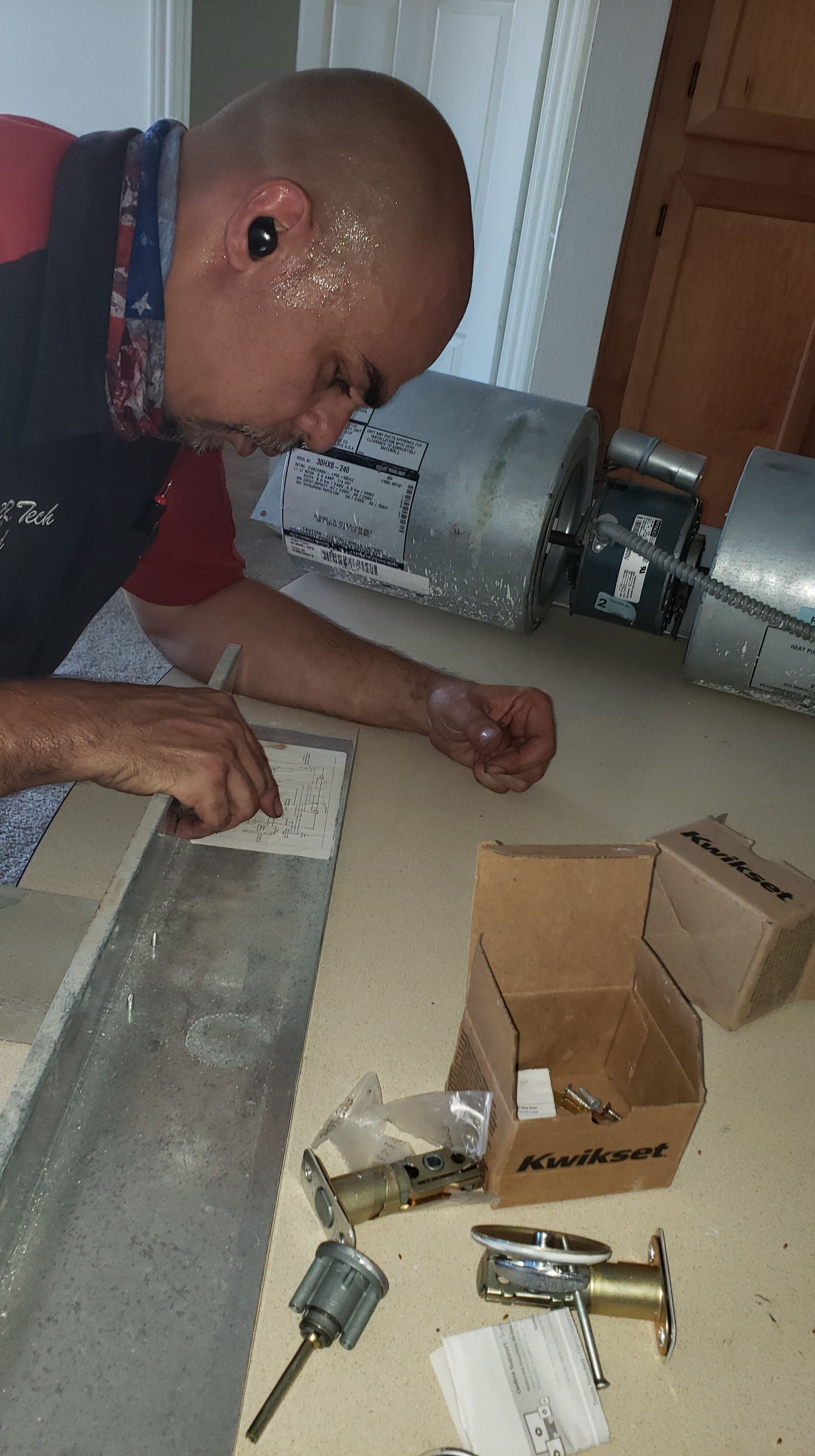 A man is sitting on the floor working on a door lock.