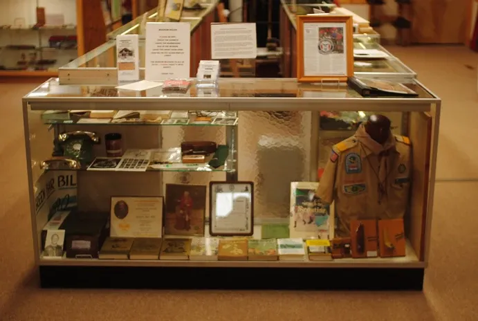 A glass display case of scouting books and clothing