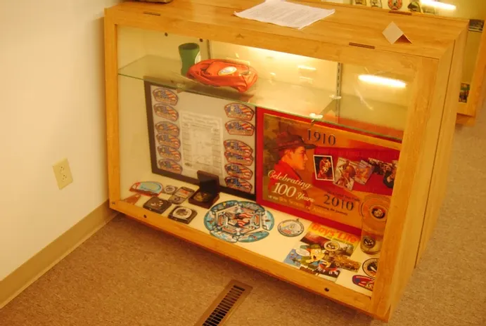 A tall glass display case of a number of scouting anniversary memorabilia