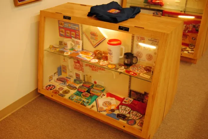 A glass display case of a large number of scouting flags, badges and mugs