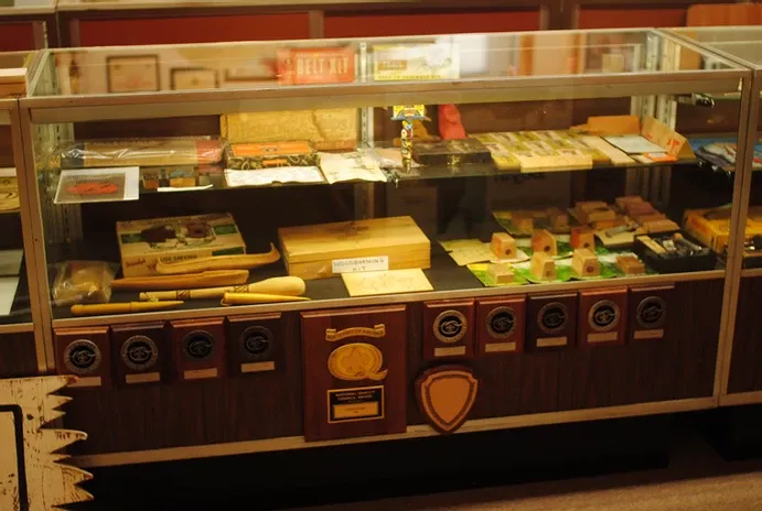 A tall glass display case of a number of carved wooden items