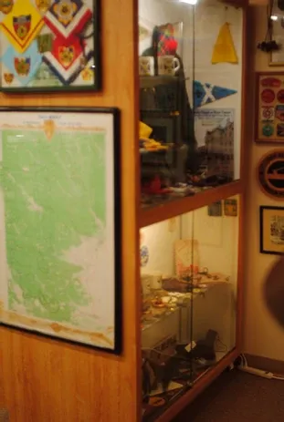A glass display case full of scouting collectibles and maps