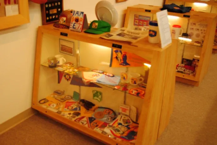 Glass display case containing a number of scouting flags and other scouting collectibles