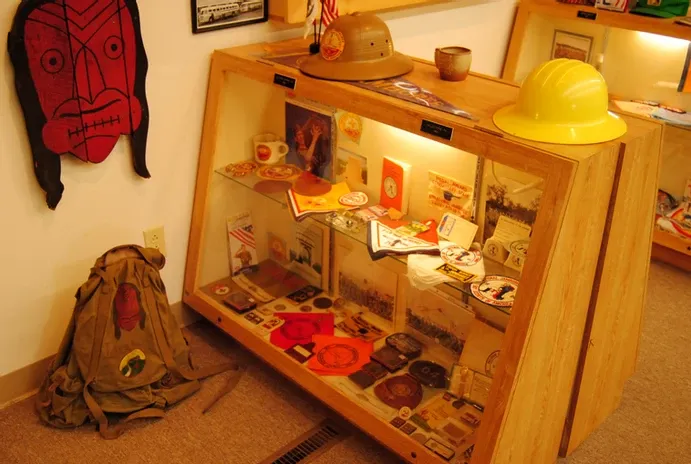 A glass display case full of scouting flags and other collectible items