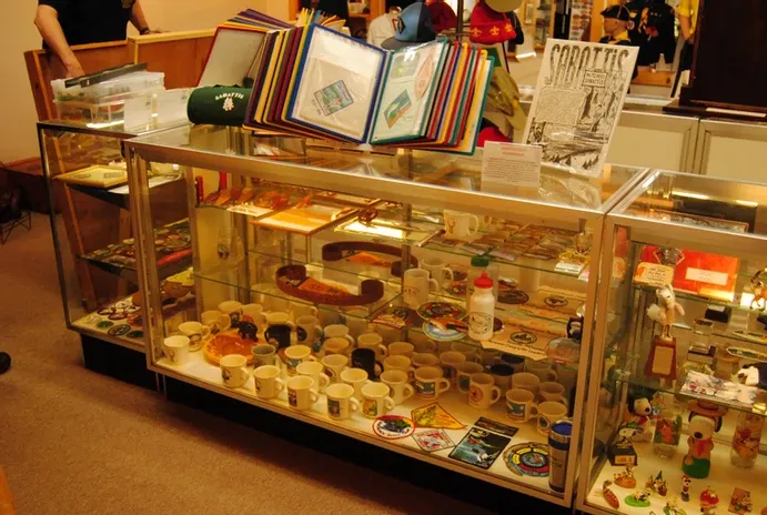 A glass display case full of scouting mugs