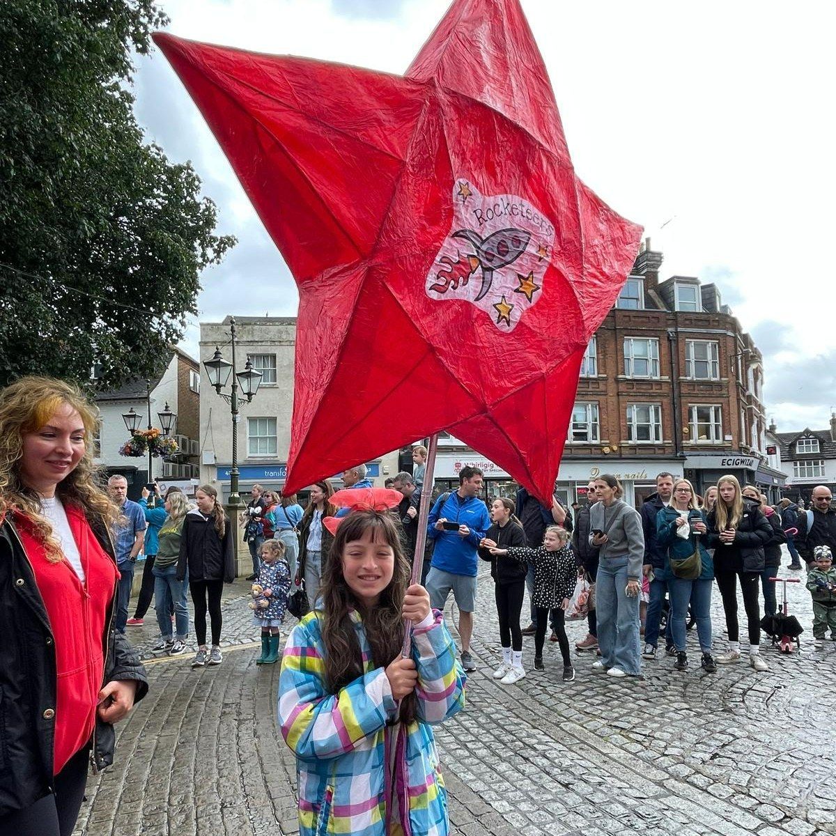 A group of people are standing around a large red star.