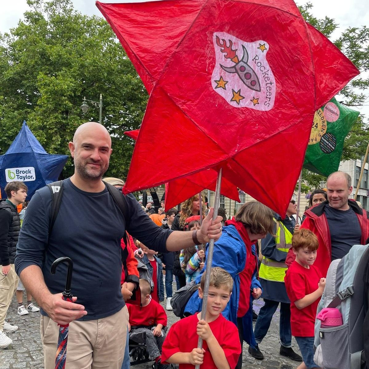 A man is holding a red flag in front of a crowd of people.