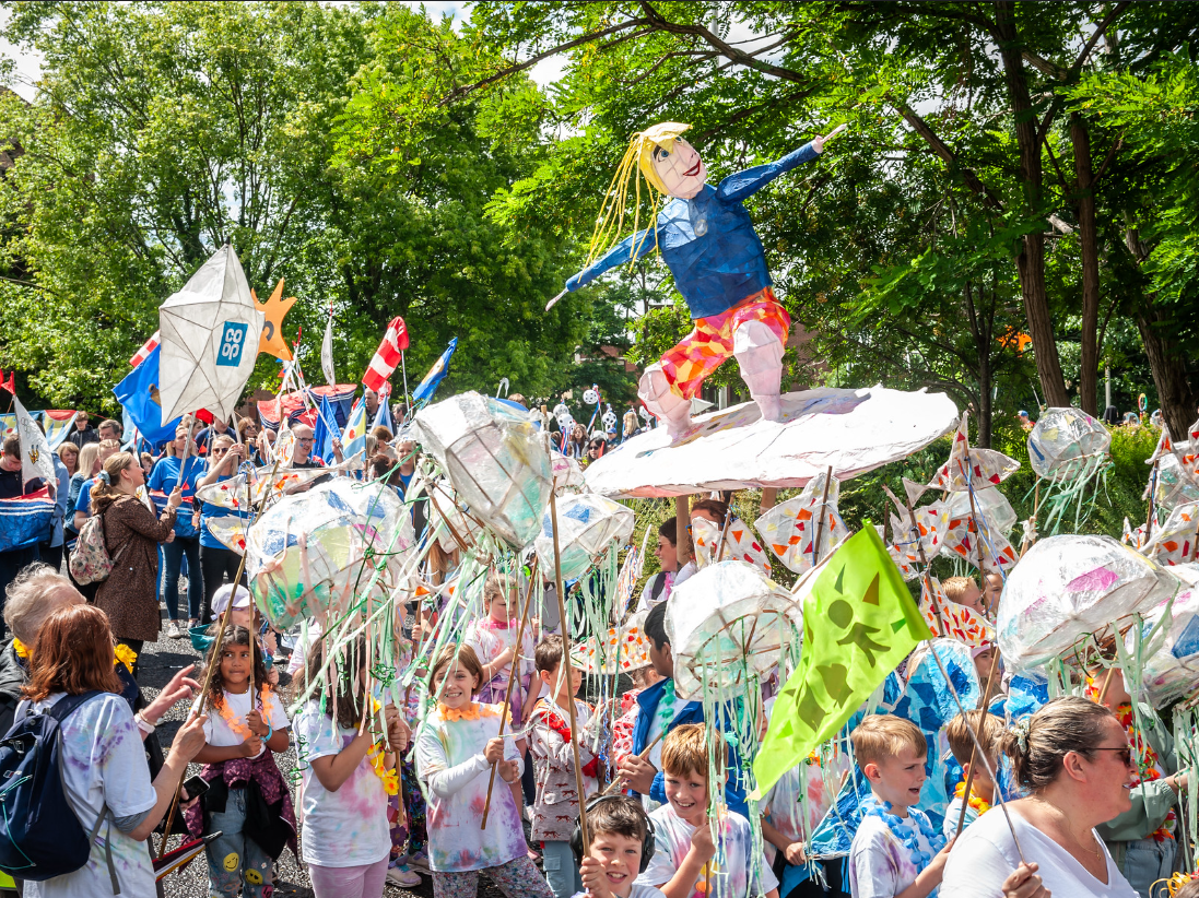 A boy is riding a surfboard in a parade.