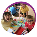 A group of children are sitting around a table playing a board game