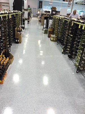 A man is standing in a wine store looking at bottles of wine.